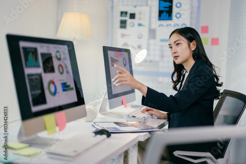 Young professional is reviewing data visualizations on her computer, engaged in a focused analysis of business performance metrics