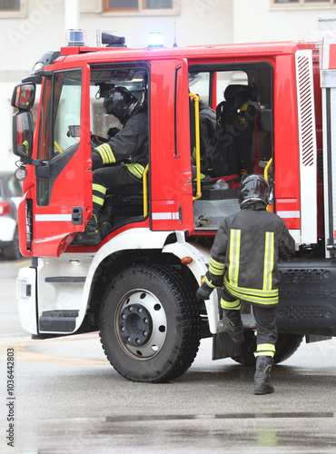 firefighters in uniform getting off a fire truck during an emergency call in the city