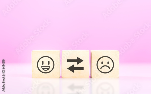 A Wooden blocks featuring smiley and sad face stickers, symbolizing the concept of choosing between happiness and sadness. The image reflects the emotional decisions we face in life