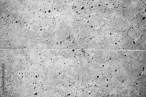 A grey wall with many holes and a rough texture