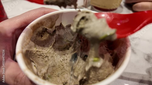 Close-up shot of eating ice cream from paper cup using plastic spoon