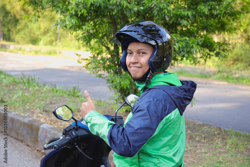 Obraz premium Back view of online taxi rider wearing green jacket and helmet, riding motorcycle while on the way to pick up customer. Transportation application concept.