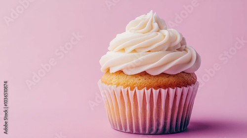 A single vanilla cupcake with white frosting sits on a pink background.