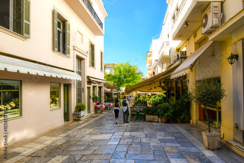 Fototapeta Naklejka Na Ścianę i Meble -  A street of souvenir shops and outdoor sidewalk cafes on a summer day in the touristic Plaka section of Athens, Greece.