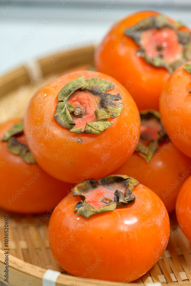 Delicious ripe persimmons in bowl on blurred background, closeup Delicious ripe persimmons in bowl on blurred background, closeup