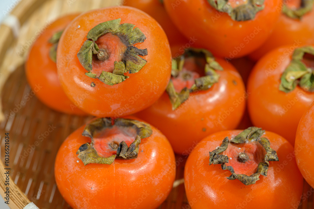 Delicious ripe persimmons in bowl on blurred background, closeup Delicious ripe persimmons in bowl on blurred background, closeup