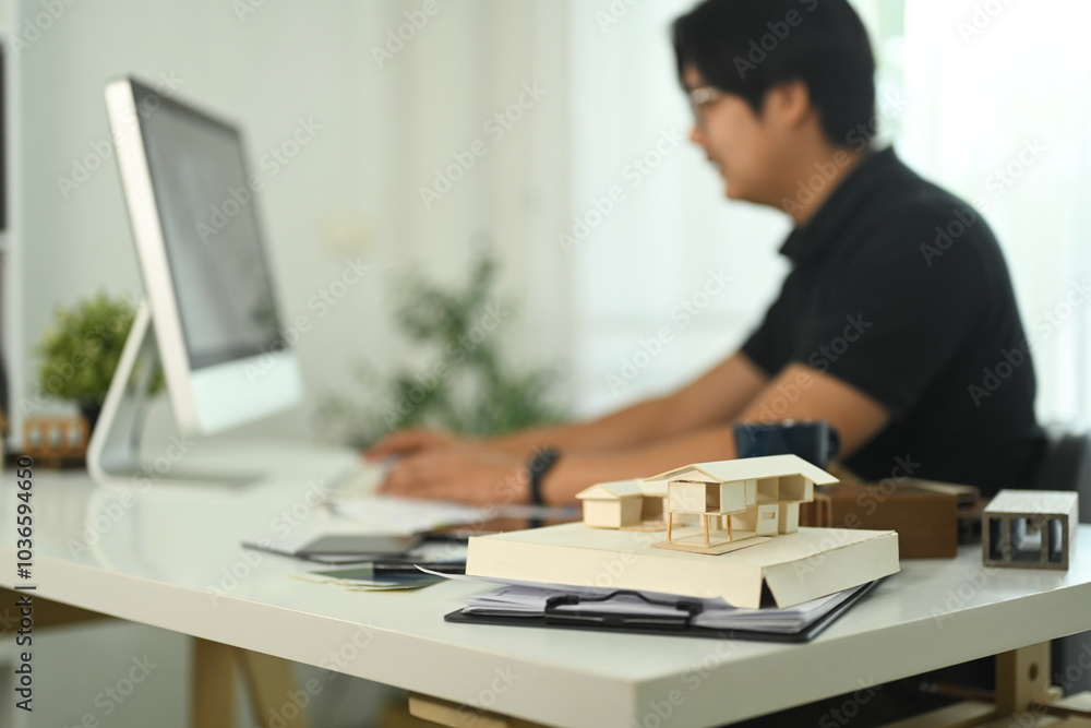 A small house model and documents on an architect workspace A small house model and documents on an architect workspace