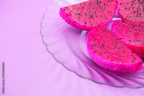 dragon fruit slices on a clear glass plate. dragon fruit slices isolated on a purple background