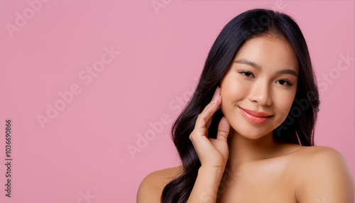 Stunning woman with radiant skin and soft makeup in a pink background