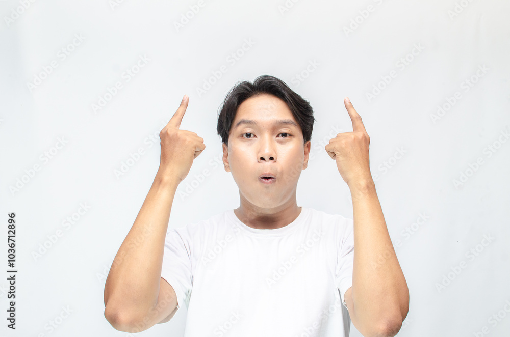 Atrractive young asian man in white t-shirt pointing his finger to advertise something. handsome asian man promoting something and pointing his finger to copy space showing discount or promotion. Atrractive young asian man in white t-shirt pointing his finger to advertise something. handsome asian man promoting something and pointing his finger to copy space showing discount or promotion.
