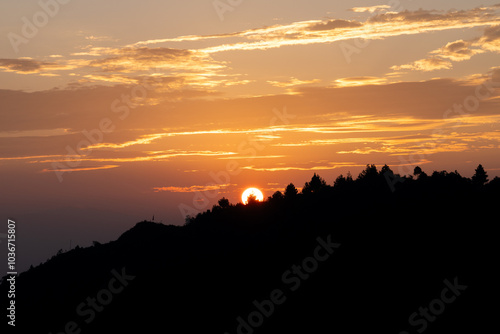 Beautiful sunrise in the mountains and sunrays in clouds in the sky