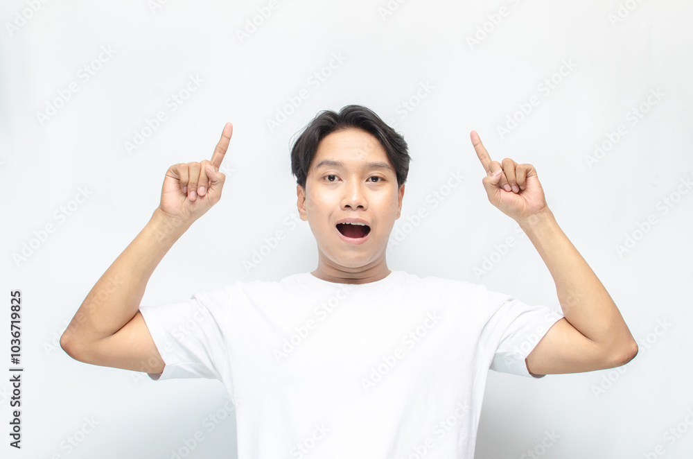 Atrractive young asian man in white t-shirt pointing his finger to advertise something. handsome asian man promoting something and pointing his finger to copy space showing discount or promotion. Atrractive young asian man in white t-shirt pointing his finger to advertise something. handsome asian man promoting something and pointing his finger to copy space showing discount or promotion.
