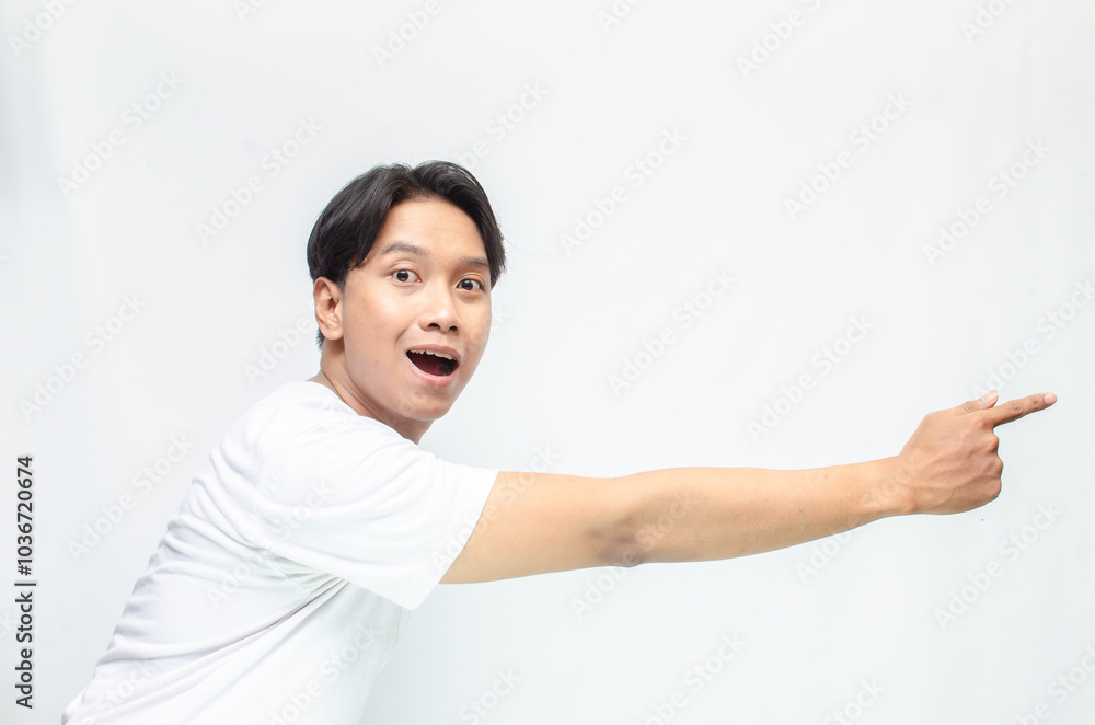 Atrractive young asian man in white t-shirt pointing his finger to advertise something. handsome asian man promoting something and pointing his finger to copy space showing discount or promotion. Atrractive young asian man in white t-shirt pointing his finger to advertise something. handsome asian man promoting something and pointing his finger to copy space showing discount or promotion.