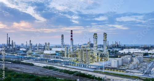 surround aerial time lapse of large refinery at dusk, petrochemical aromatic industry landscape.