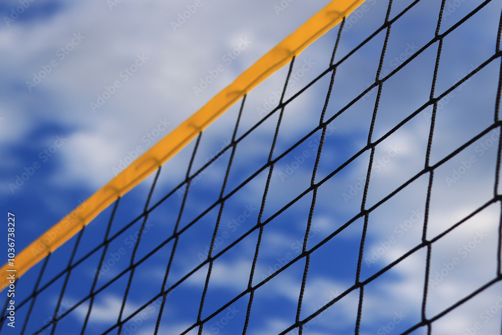 Beach volleyball net close-up. Fragment of a volleyball net on the beach against the blue sky. Sport, beach volleyball. Active recreation concept. Background. Detail of the yellow net. Sports ground Beach volleyball net close-up. Fragment of a volleyball net on the beach against the blue sky. Sport, beach volleyball. Active recreation concept. Background. Detail of the yellow net. Sports ground