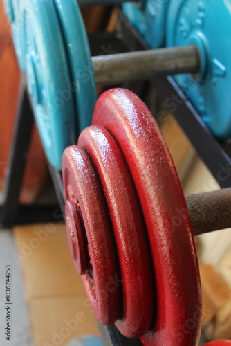 A close up of some red and teal weightlifting dumbells on a rack. 