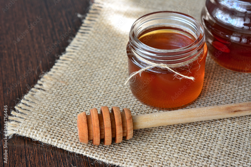 a jar of honey next to a jar of honey with a wooden stick a jar of honey next to a jar of honey with a wooden stick