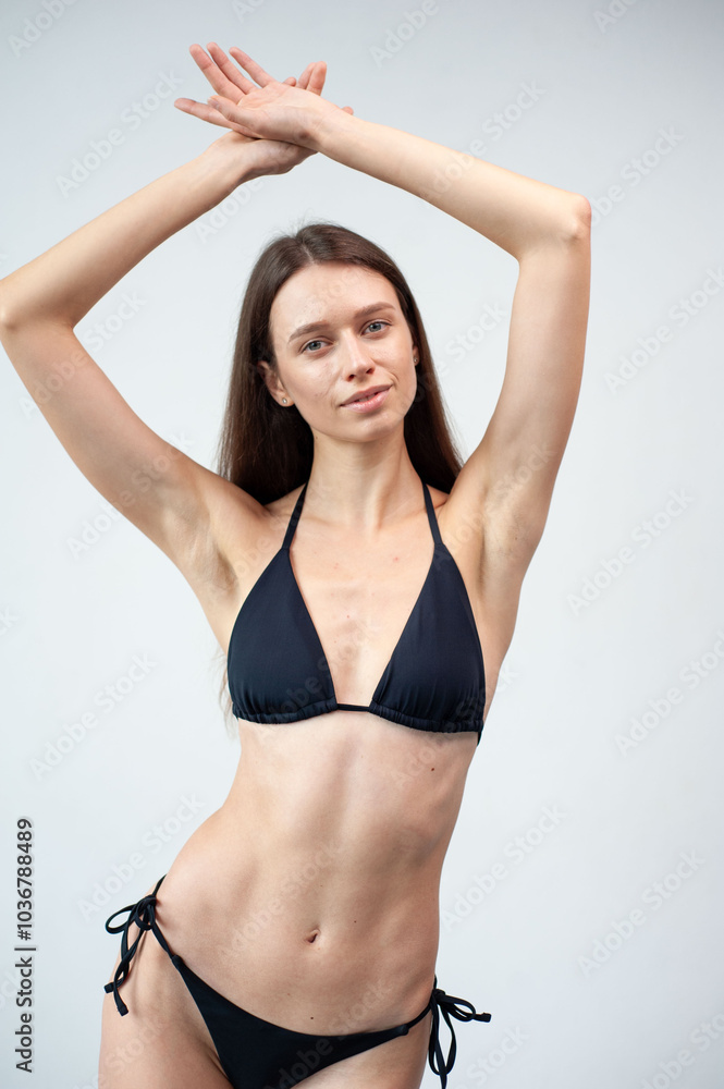 Obraz premium Confidence always completes your look. Studio portrait of an attractive young woman posing in a bikini against a grey background.