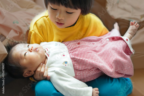 妹の首を支えて抱っこする男の子/A boy supporting his sister's neck and holding her in his arms photo