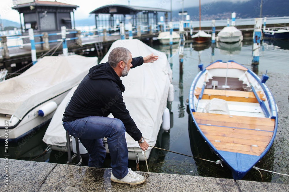 man mooring a boat on lake Iseo Italy man mooring a boat on lake Iseo Italy