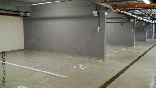 Empty underground parking garage with rows of spaces, modern design, bright lights, and strong shadows. Safe and secure urban infrastructure photo