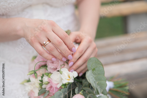 Hands of the bride with golden ring and manicure close-up on wedding bouquet flower. Poster format design