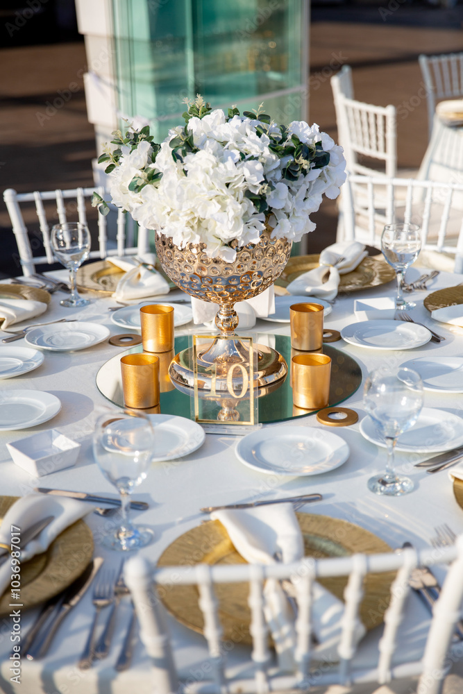 Glamorous wedding table setting with gold accents, white hydrangeas, and mirrored chargers