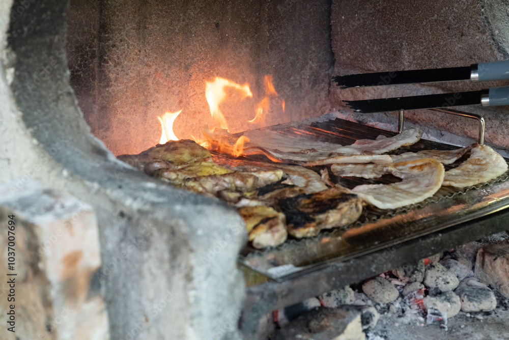 Open flame barbacue made with coals and burnt chicken breasts and bacon cooking and grilling on it Open flame barbacue made with coals and burnt chicken breasts and bacon cooking and grilling on it