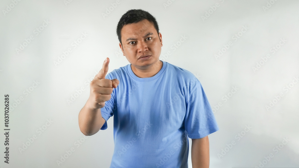 Fototapeta premium A young Indonesian man wearing a blue t-shirt with an angry face facing forward