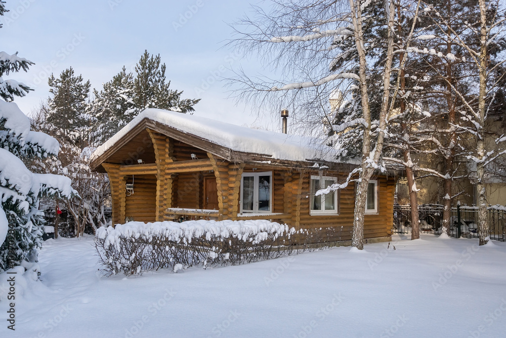 A delightful winter landscape with a wooden log house. Snow-covered trees in the rays .of the setting sun. A delightful winter landscape with a wooden log house. Snow-covered trees in the rays .of the setting sun.