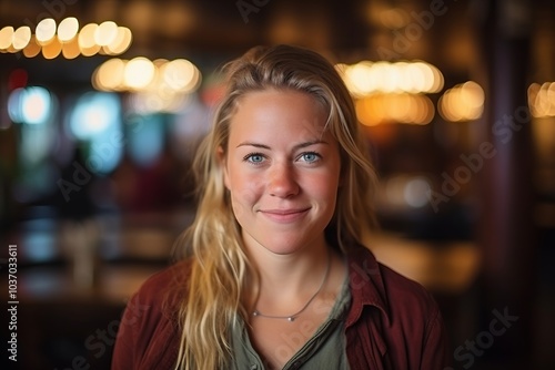 Portrait of a beautiful young woman smiling in a pub, looking at the camera.