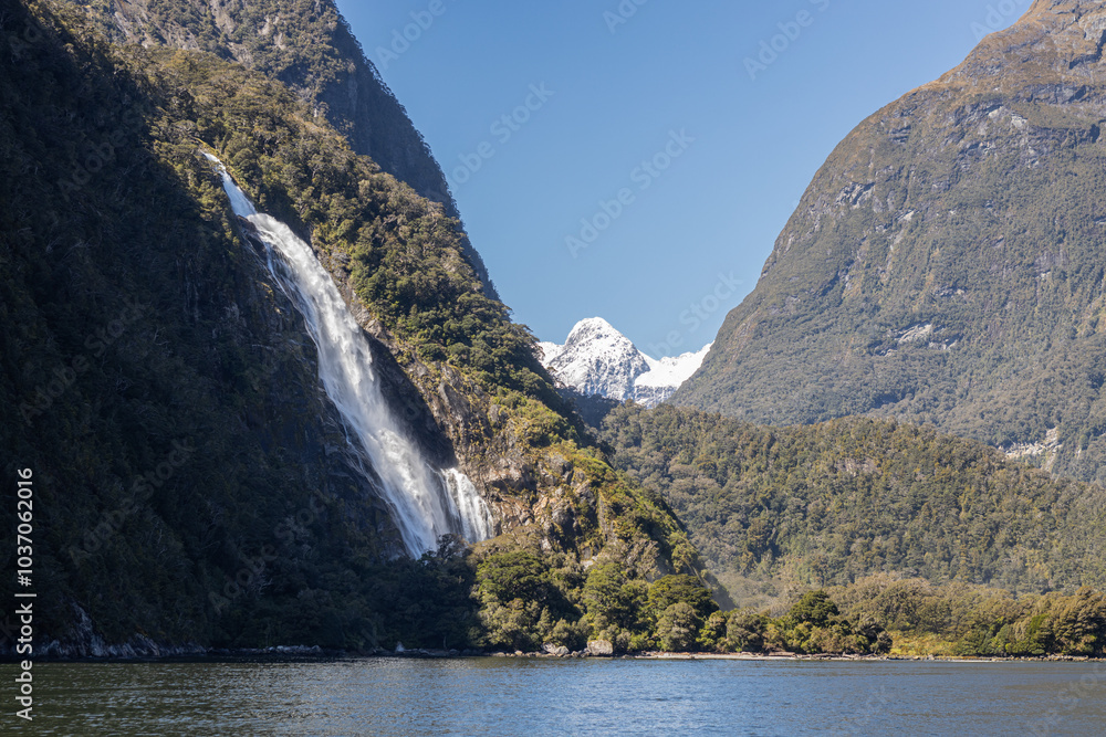 Waterfall cascading down mountain into milford sound, new zealand Waterfall cascading down mountain into milford sound, new zealand