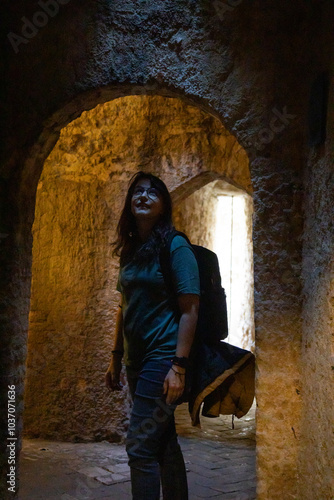 Young woman exploring ancient stone ruins while carrying backpack