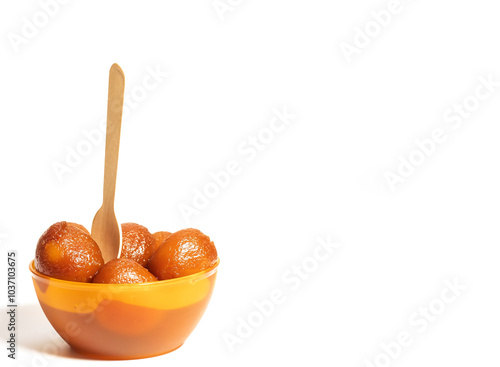 Traditional Indian dessert Gulab Jamun in orange bowl with wooden spoon