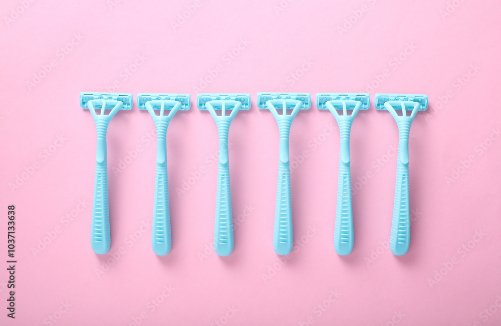Blue plastic razors on a pink background. Top view Blue plastic razors on a pink background. Top view