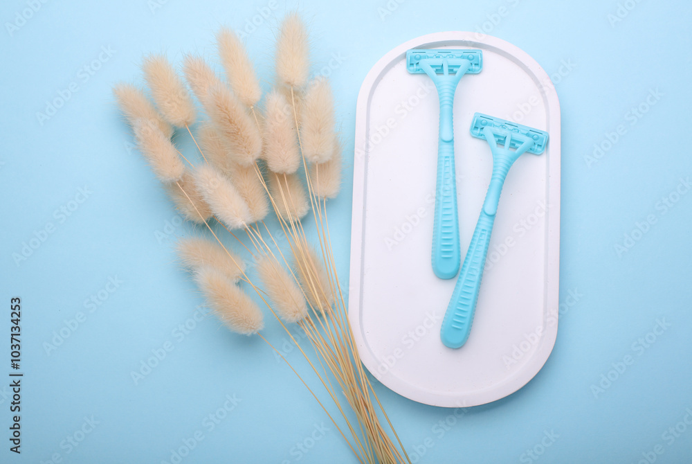 Blue disposable razors with lagurus flowers in plaster tray, blue background. Blue disposable razors with lagurus flowers in plaster tray, blue background.