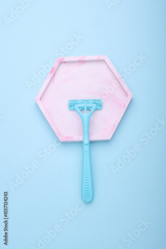 Blue disposable razor with plaster tray, blue background.