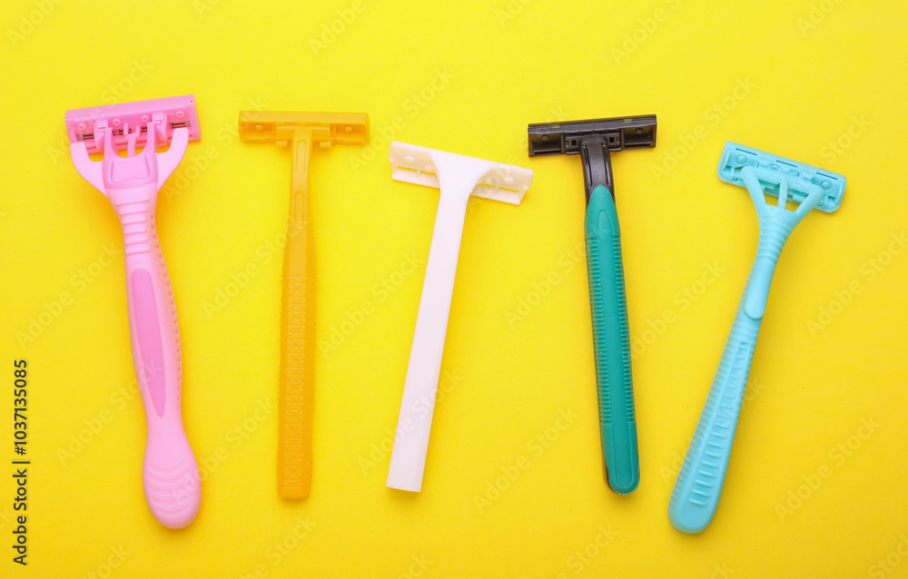 Different disposable razors on a yellow background. Top view Different disposable razors on a yellow background. Top view