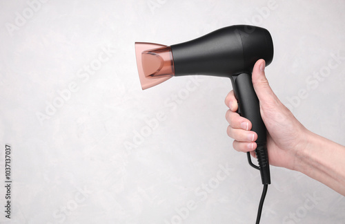 Hand holding hair dryer on grey background