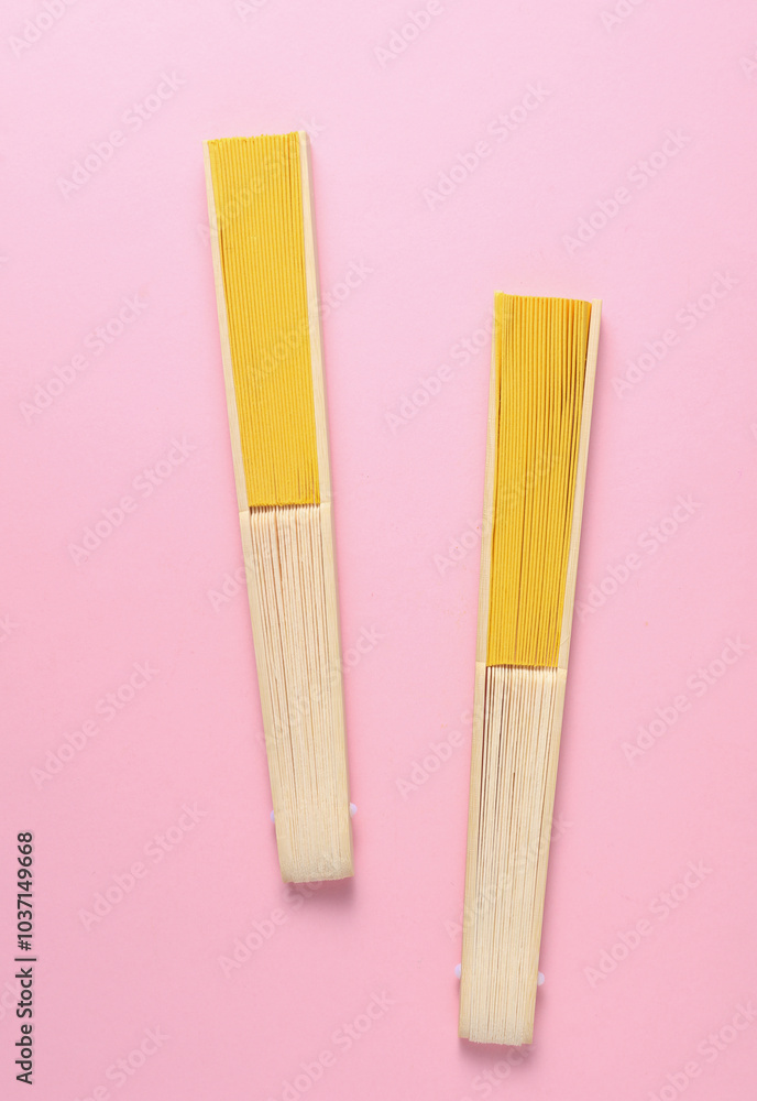 Traditional yellow Asian hand fans on pink background Traditional yellow Asian hand fans on pink background