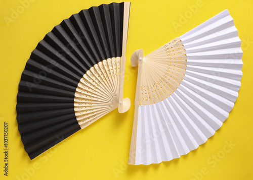 Traditional black Asian hand fans on yellow background photo