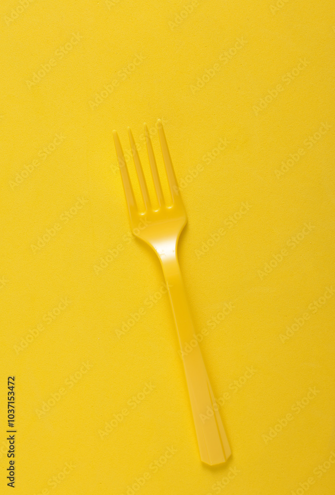 Plastic fork on yellow background close up Plastic fork on yellow background close up