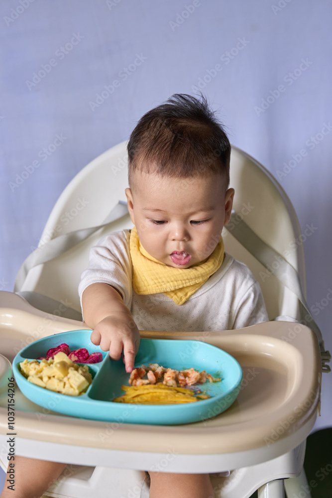 9 month old Asian baby boy is learning to eat, with food on the table, the baby eats and commands himself, it seems a bit messy 9 month old Asian baby boy is learning to eat, with food on the table, the baby eats and commands himself, it seems a bit messy