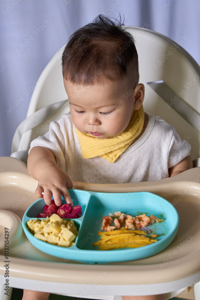 9 month old Asian baby boy is learning to eat, with food on the table, the baby eats and commands himself, it seems a bit messy 9 month old Asian baby boy is learning to eat, with food on the table, the baby eats and commands himself, it seems a bit messy