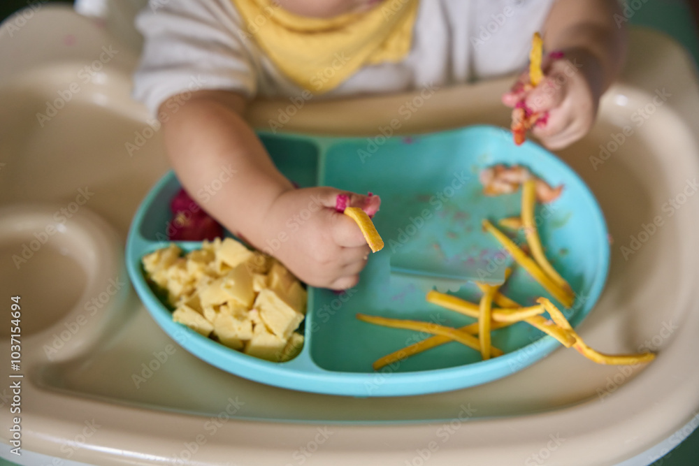 9 month old Asian baby boy is learning to eat, with food on the table, the baby eats and commands himself, it seems a bit messy 9 month old Asian baby boy is learning to eat, with food on the table, the baby eats and commands himself, it seems a bit messy