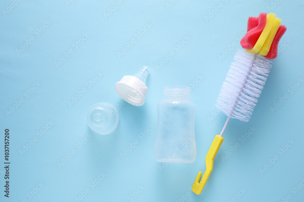 Newborn feeding bottle and washing brush on blue background. Top view Newborn feeding bottle and washing brush on blue background. Top view