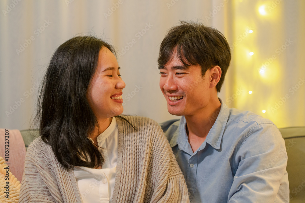 Happy married Asian couple hugging, sitting on cozy couch together, overjoyed laughing woman and man having fun, enjoying leisure time, relaxing on sofa in living room at home, good relationship Happy married Asian couple hugging, sitting on cozy couch together, overjoyed laughing woman and man having fun, enjoying leisure time, relaxing on sofa in living room at home, good relationship