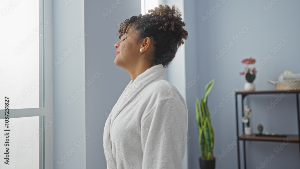 Woman relaxing indoors wearing a white robe at a wellness center, basking in the natural light from the window Woman relaxing indoors wearing a white robe at a wellness center, basking in the natural light from the window