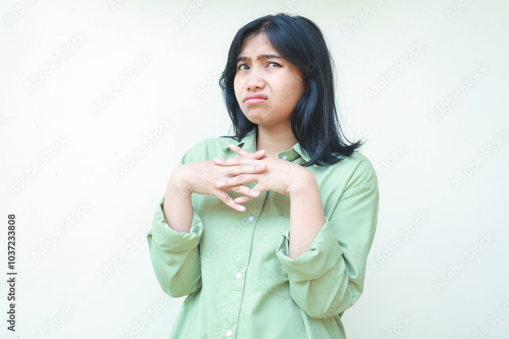 thoughtful asian woman with dark dark hair wearing green oversized shirt looking away with stick finger thingking about something isolated on white background