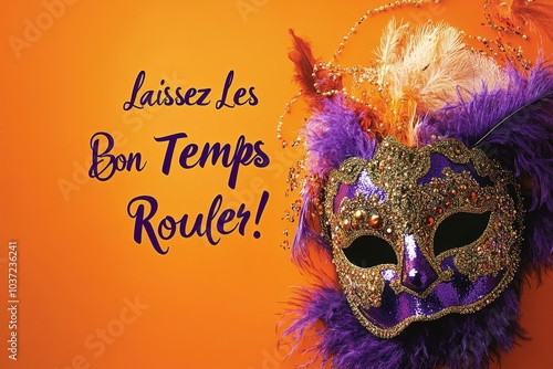 Purple and gold mardi gras mask with feathers is lying on an orange background with the french saying laissez les bon temps rouler photo